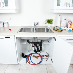 The underneath of a sink with detached water hoses.