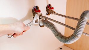 A plumber repairs the water pipes in the bathroom with the help of wrench