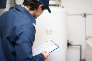 A plumber evaluating the condition of a tank water heater.